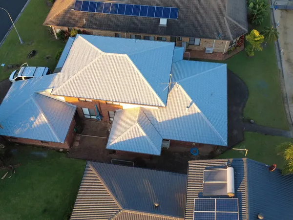 Aerial view of a freshly restored light roof on a home near the water